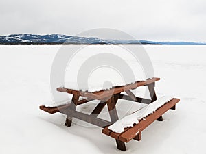 Camp table benches and snowy frozen lake landscape