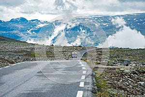 Camper car in norwegian mountains. Tourism vacation and travel. Caravan car RV travels on the mountain road, pass Norway