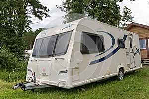 Camper trailer for traveling standing on shore of the lake in summer