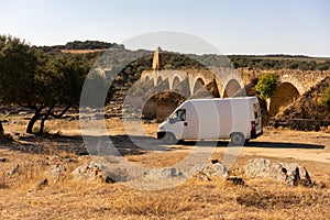 Camper van in Alentejo landscape with abandoned destroyed Ajuda bridge behind, in Portugal