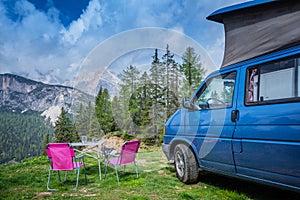 Camper van in the amazing landscape views of forest, mountains. Van road trip holiday and outdoor summer adventure