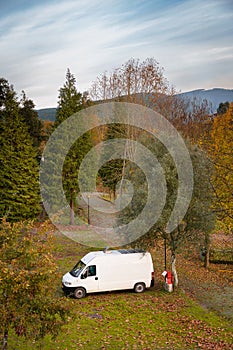 Camper Van charging electricity on a campsite with trees around