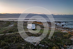 Camper van motorhome with solar panels drone aerial view on a sea landscape with mountains living van life in Galiza, Spain photo