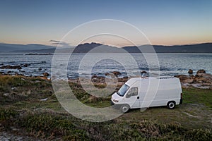 Camper van motorhome with solar panels drone aerial view on a sea landscape with mountains living van life in Galiza, Spain photo