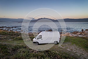 Camper van motorhome with solar panels drone aerial view on a sea landscape with mountains living van life in Galiza, Spain photo
