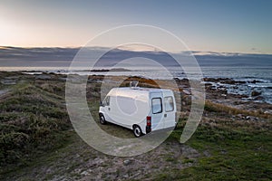 Camper van motorhome with solar panels drone aerial view on a sea landscape with mountains living van life in Galiza, Spain photo