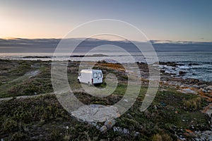 Camper van motorhome with solar panels drone aerial view on a sea landscape with mountains living van life in Galiza, Spain