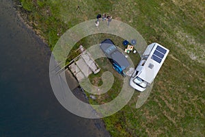 Camper van motorhome with solar panels drone aerial view of two couples living van life near a river and grass in Portugal at photo