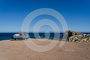 Camper van parked on the beach in front of the blue sea during holidays