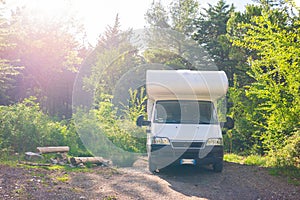 Camper van parked in forest, vanlife in Tuscany, Italy. Scenic sun burst in backlight. Unique green landscape. Alternative