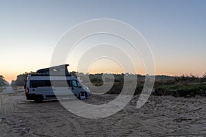 Camper van parked at an idyllic beach access at sunrise