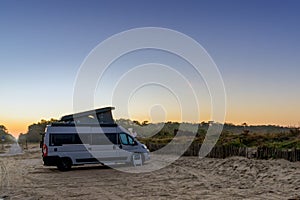 Camper van parked at an idyllic beach access at sunrise