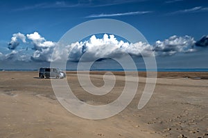 Camper Van On The Sandy Beach Of Burry Port At Low Tide In Wales, United Kingdom