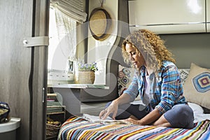 Camper van travel nomadic lifestyle people concept with serene woman reading a book sitting on bed in motorhome bedroom. Vanlife