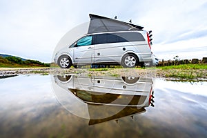 Campervan or motorhome camping on rainy day with rain puddles