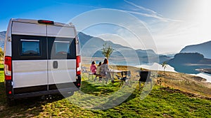 Campervan, Motorhome RV parked next to the lake or river in Bosnia and Herzegovina. Family with camper van or motor home eating