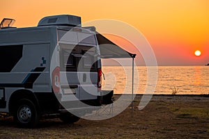 Campervan is parked on the beach at sunset