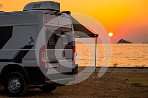 Campervan is parked on the beach at sunset