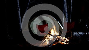 Campfire burning, tent and chairs around, advertisement to camping tours in wood
