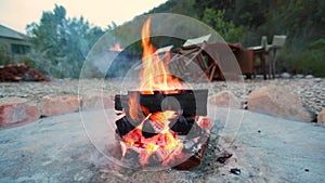 A campfire burns in a fire pit at a safari camp