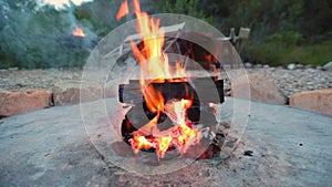 A campfire burns in a fire pit at a safari camp with another in the background