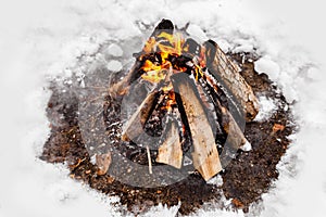 Campfire burns in the snow in the woods.. campfire burning in cold winter. Snow, forest and fire. Winter. Tourism