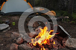 Campfire in campsite with tent set up and other camp necessities in the adventurous mountains photo