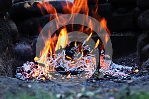 Campfire in the garden with wood burning at the afternoon. Long exposure. Burned logs slowly loses their calorific value. Typical