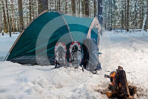A campfire near a tent in a winter camping