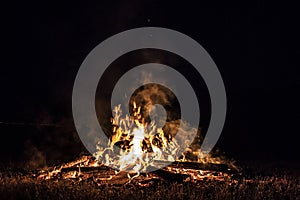 Campfire at night, with its soothing flickering flames and red and orange glow of the burning logs at dark night