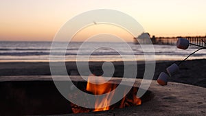 Campfire pit in California USA. Camp fire on ocean sea beach, roasting toast marshmallow on bonfire.