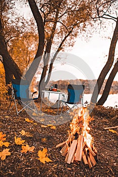 camping autumn place with bonfire and portable chairs