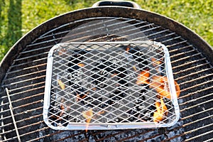 Camping BBQ seen alight while located in a full size BBQ.