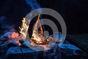 Camping bonfire with yellow and red flames in summer, forest. Copy space photo