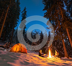 Camping with campfire and tent outdoors in winter photo