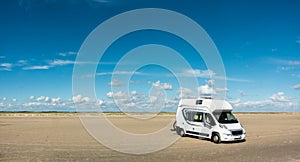 Camping Car RV standing on empty sand beach panorama on sunny day. Romo Bilstrand, Lakolk Strand, Denmark. photo