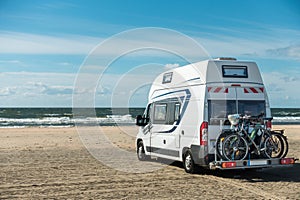 Camping Car RV standing on sand beach at waterfront on sunny day. Romo Bilstrand, Lakolk Strand, Denmark. photo