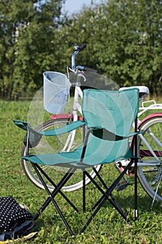 Camping chair and bike on a green meadow. Autumn picnic