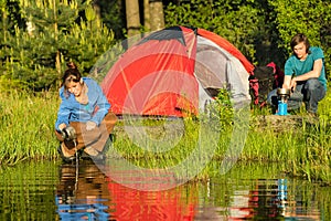 Camping couple heating supper and washing pot