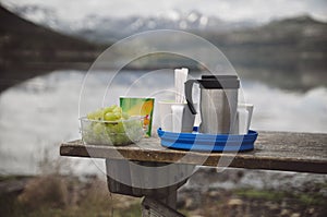 Camping cuisine. Picnic food on wooden table by the lake.