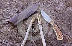 Camping damascus blade knife, sheath and sticks on wood log