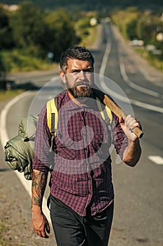 Camping equipment. Man hiker with tourist backpack and axe stand on road