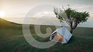 Camping.Evening scence.Tent under the big tree on a meadow,hill,mountains with sea background.