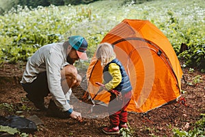 Camping family vacations child helps father to set tent travel lifestyle hiking gear tourism outdoor