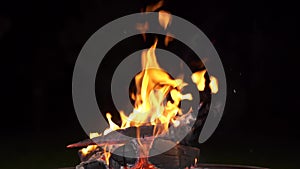 Camping fire in the dark. Firewood burns with coals. Tongues of flame rise up on a black background outside. Light a