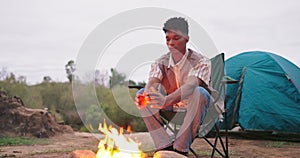 Camping, fire and man warm hands in nature for adventure, outdoor holiday and vacation. Travel, weekend and person relax