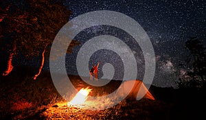 Camping fire and tent under the amazing starry sky with lot of shining stars