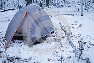 Camping in gray tent in winter forest