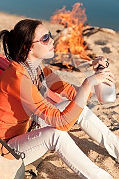 Camping happy woman by campfire on beach