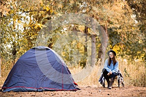 Camping holiday, tourist traveler woman in sweater and black hat ralaxing in camp tent in forest, rest vacation concept